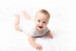 Smiling baby propped up on their arms during tummy time